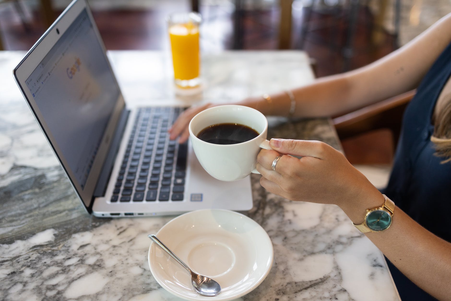 a woman drinking coffee while googling on a laptop