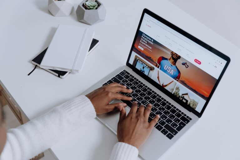 person using a macbook pro on a white table